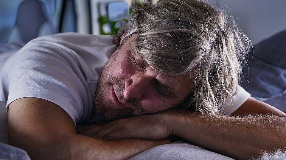 Mann schläft in einem Wohnwagen