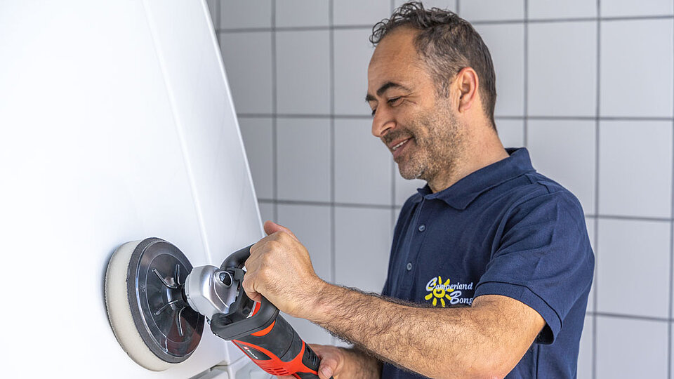 Mann poliert weißen Wohnwagen 