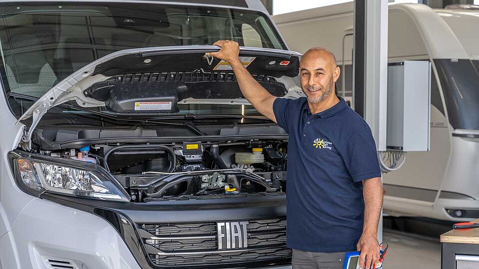 Mann hält Motorhaube eines Wohnmobils